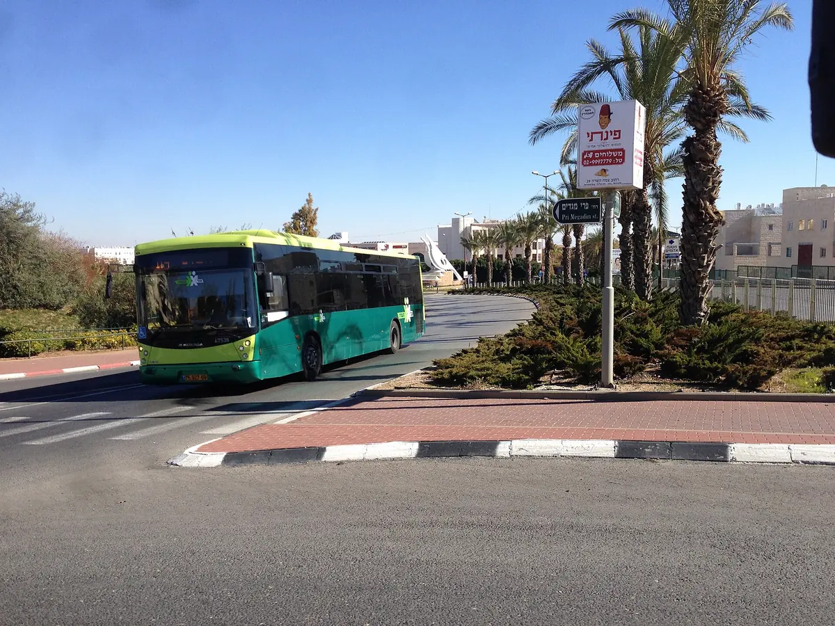 A green city bus on Derech Har HaBayit at the corner of Pri Megadim St