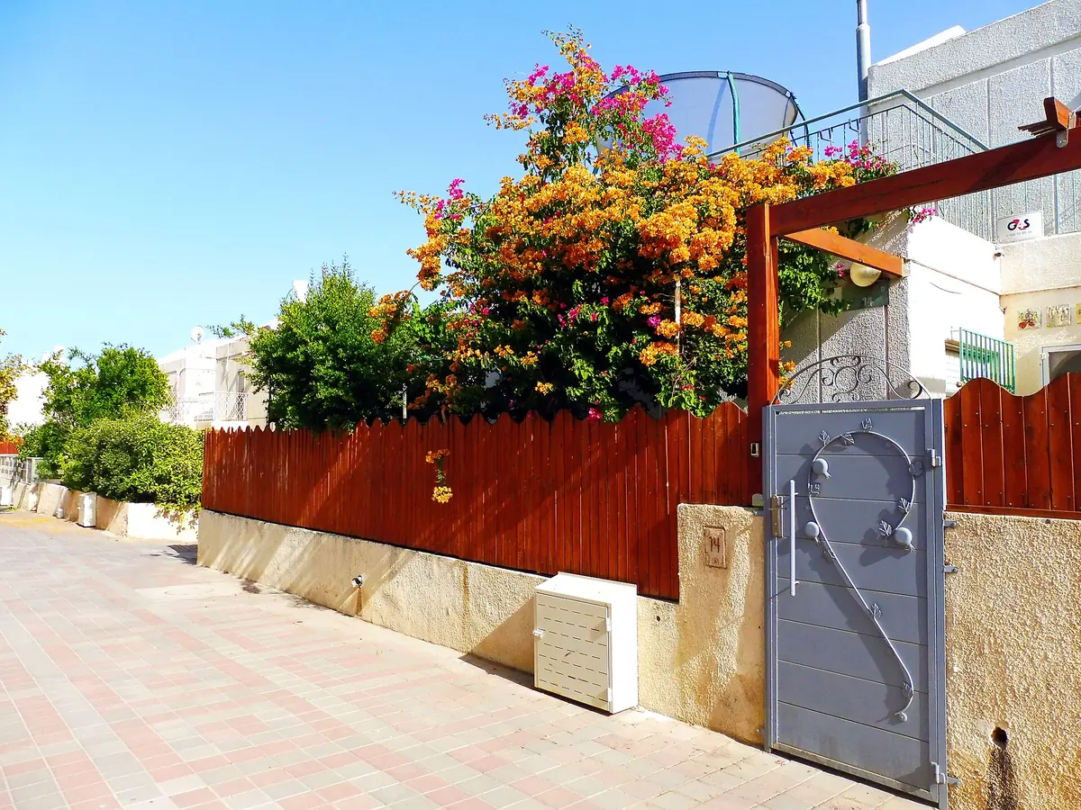 A paved alley with bougainvillea and garden gates in HaNachalim