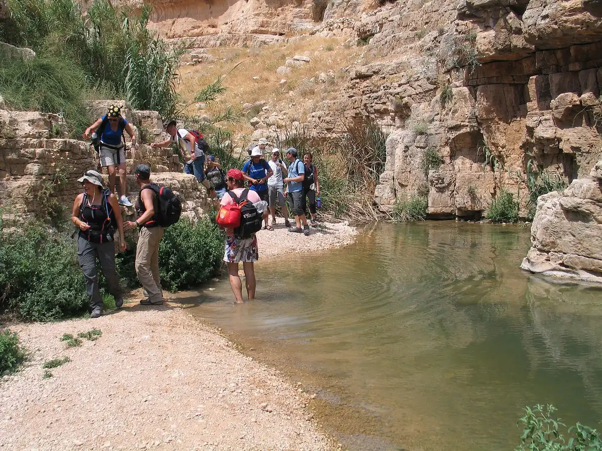 Hikers beside the Nahal Prat stream under the canyon cliffs between Ein Prat and Ein Mabua
